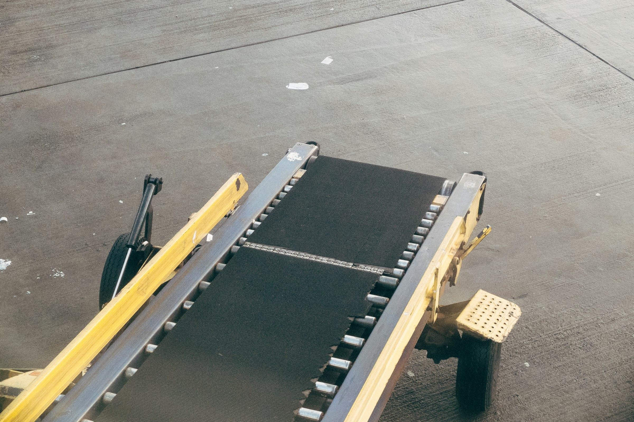 Compact steel-framed belt conveyor standing on a concrete workshop floor