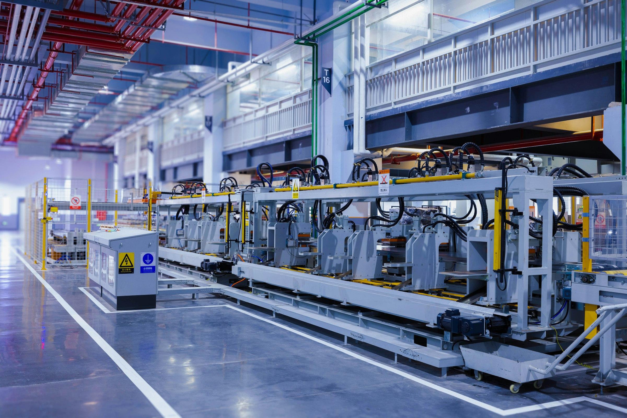 Long automated machine line running through a bright, modern factory hall