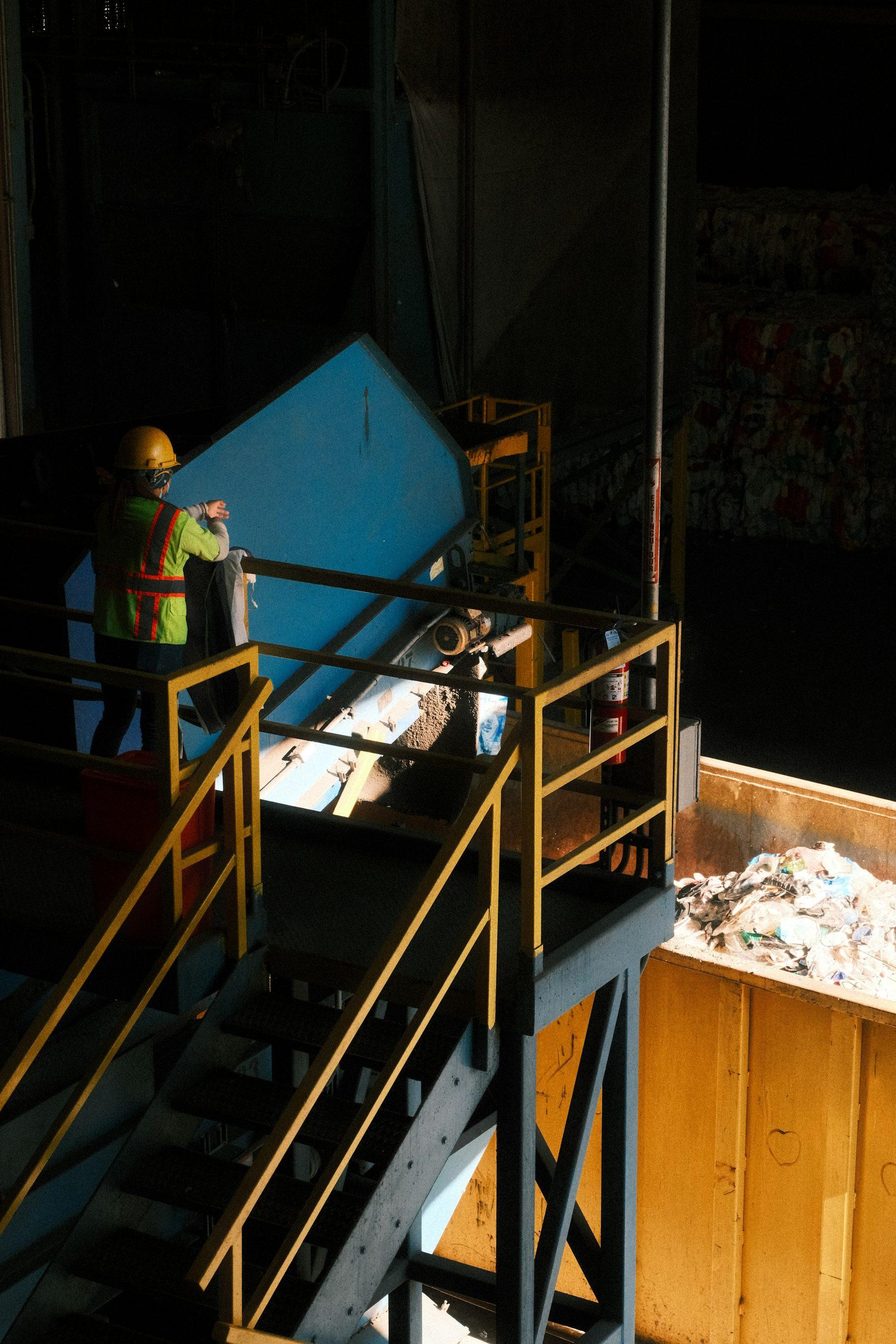 Worker on a steel platform feeding material onto the conveyor of a recycling line