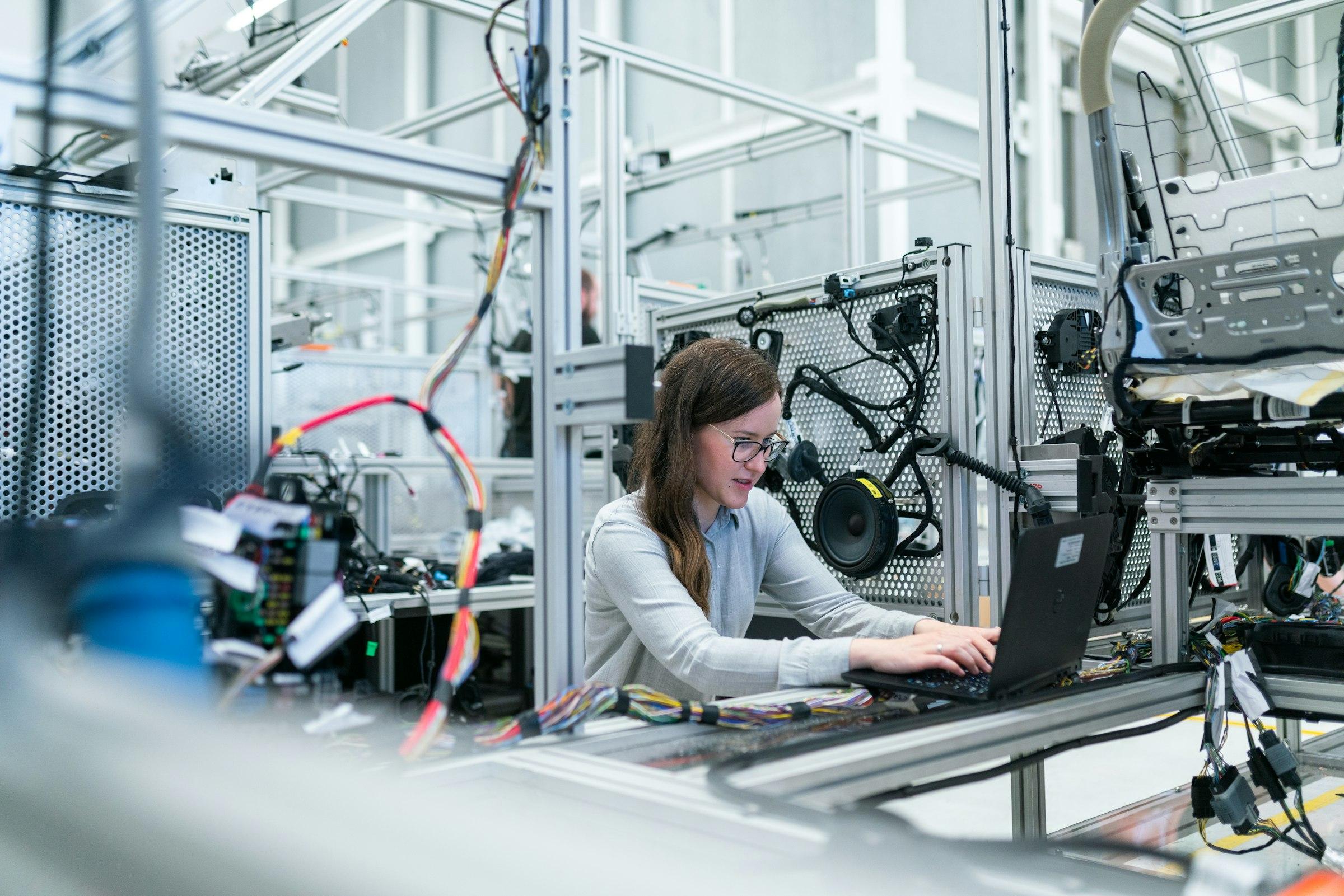 Engineer working on a laptop inside an automated machine test rig