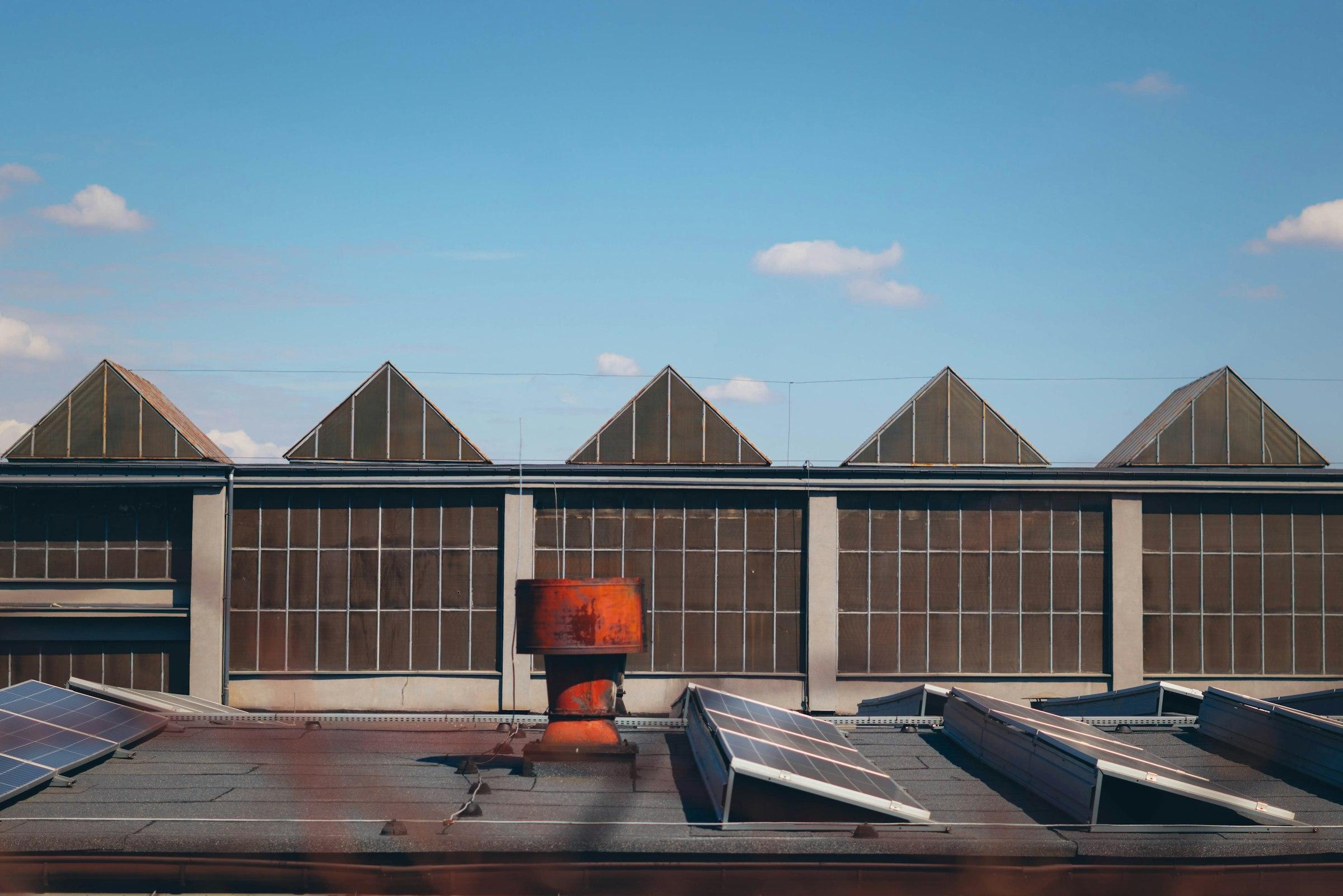 Sawtooth factory roof with north-light glazing under a clear blue sky