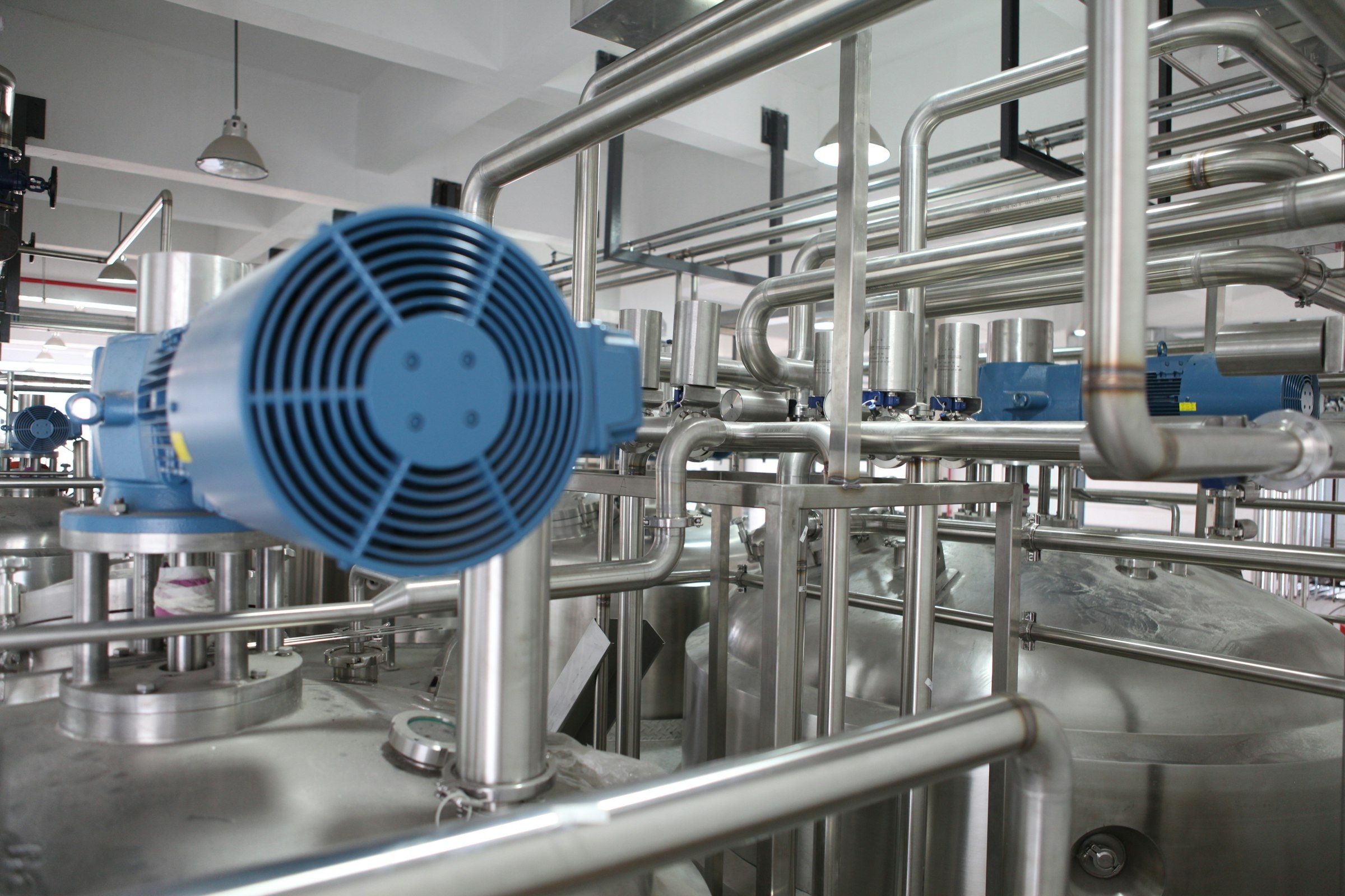 Stainless-steel industrial processing line with an electric motor and pipework in a daylit plant