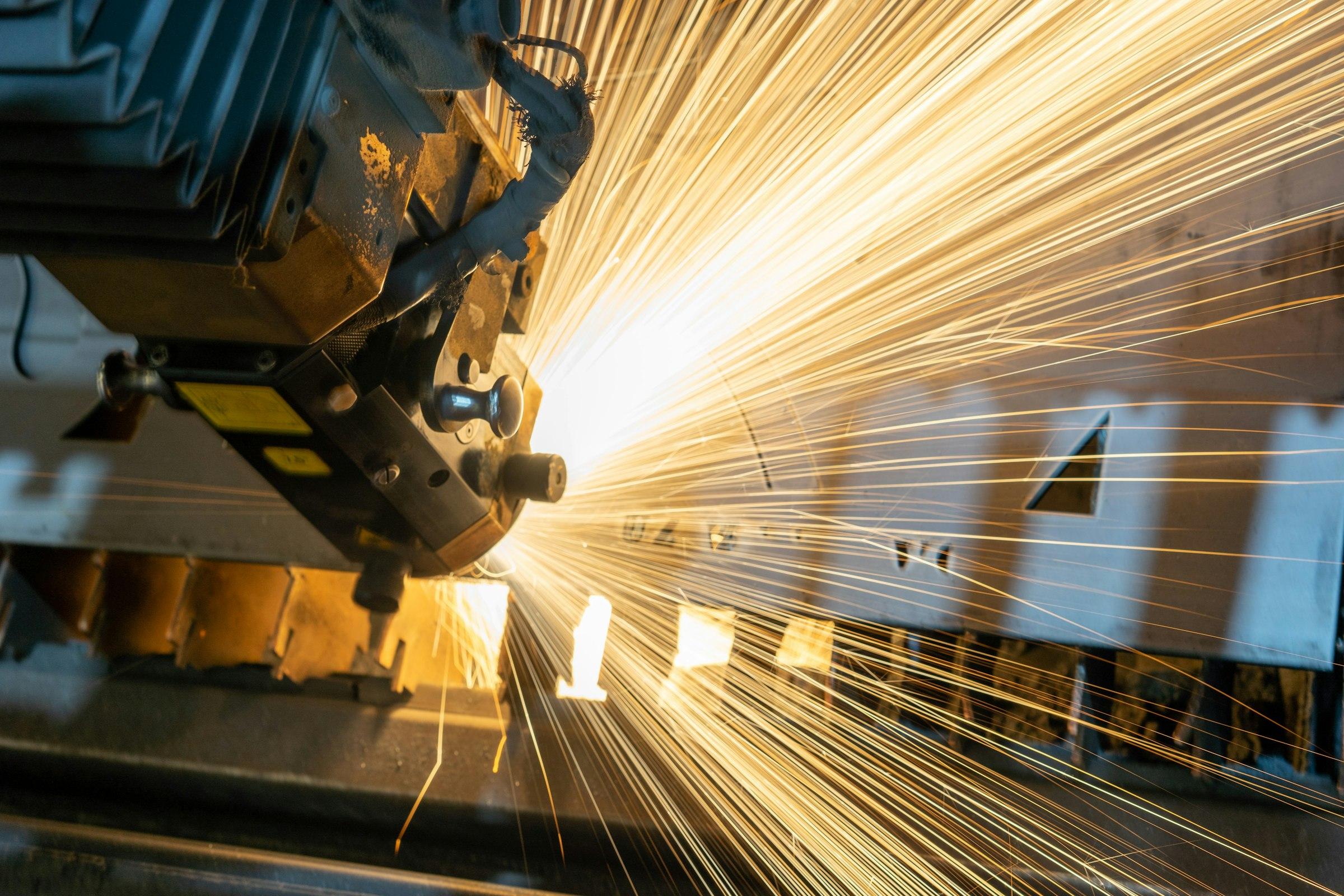 Cutting head slicing through steel plate with a fan of bright sparks