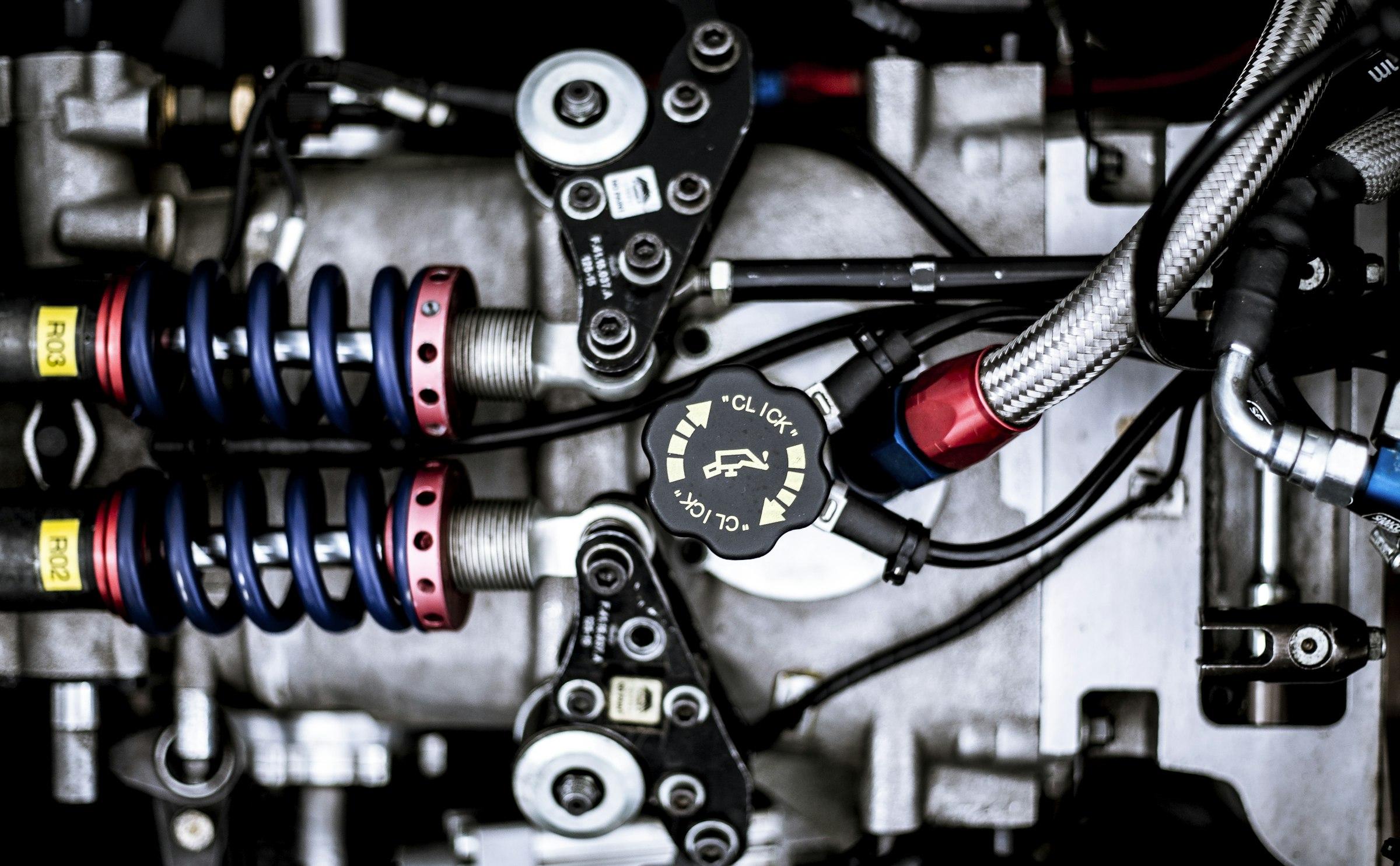 Close-up of springs, linkages and braided hoses inside a machine assembly